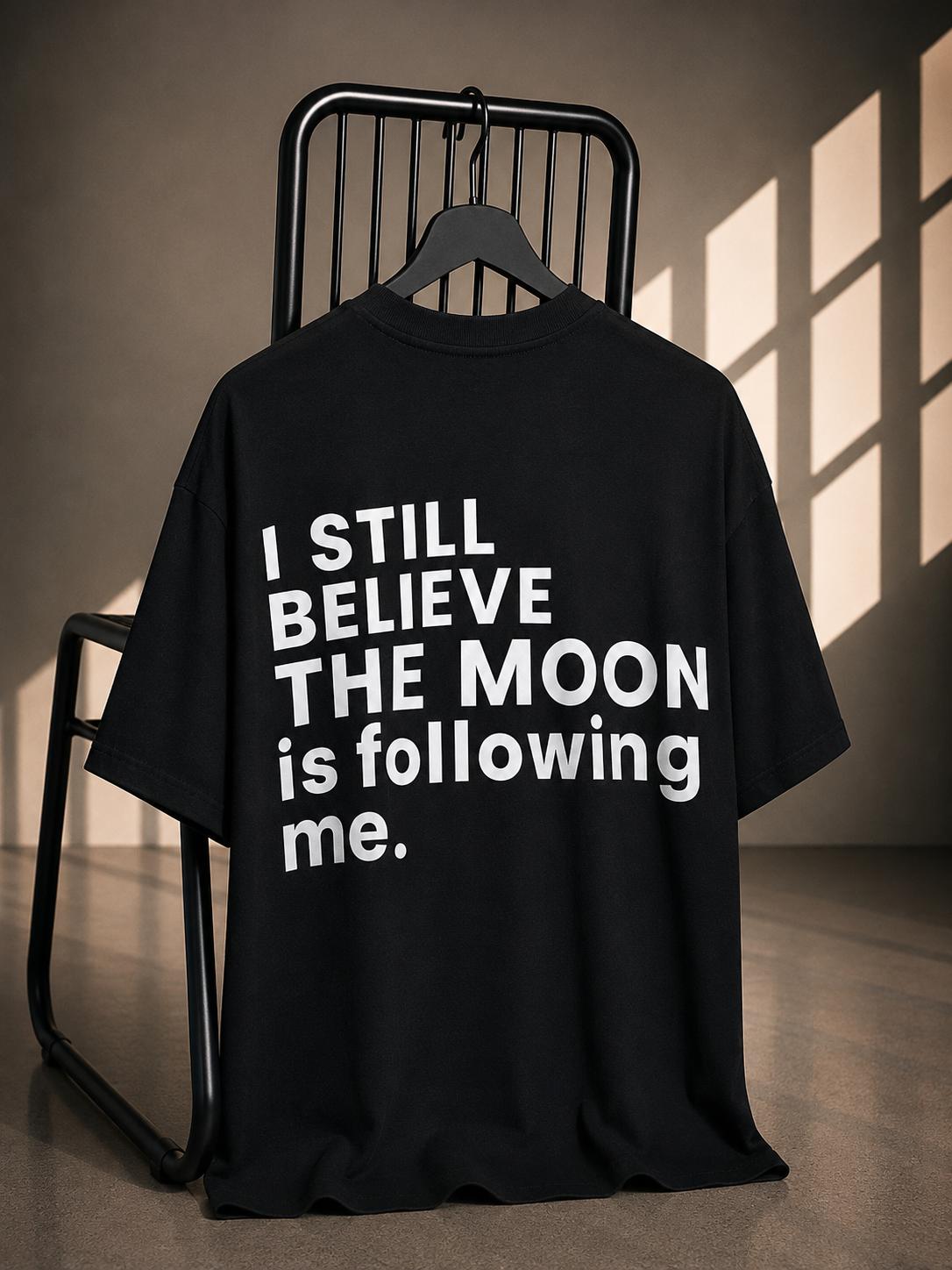Black oversized graphic T-shirt with I Still Believe the Moon Is Following Me back print.