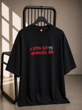Black oversized unisex graphic T-shirt with "A Little Bit Dramatic" typography and cherry artwork, made from 220–240 GSM bio-washed French Terry cotton.