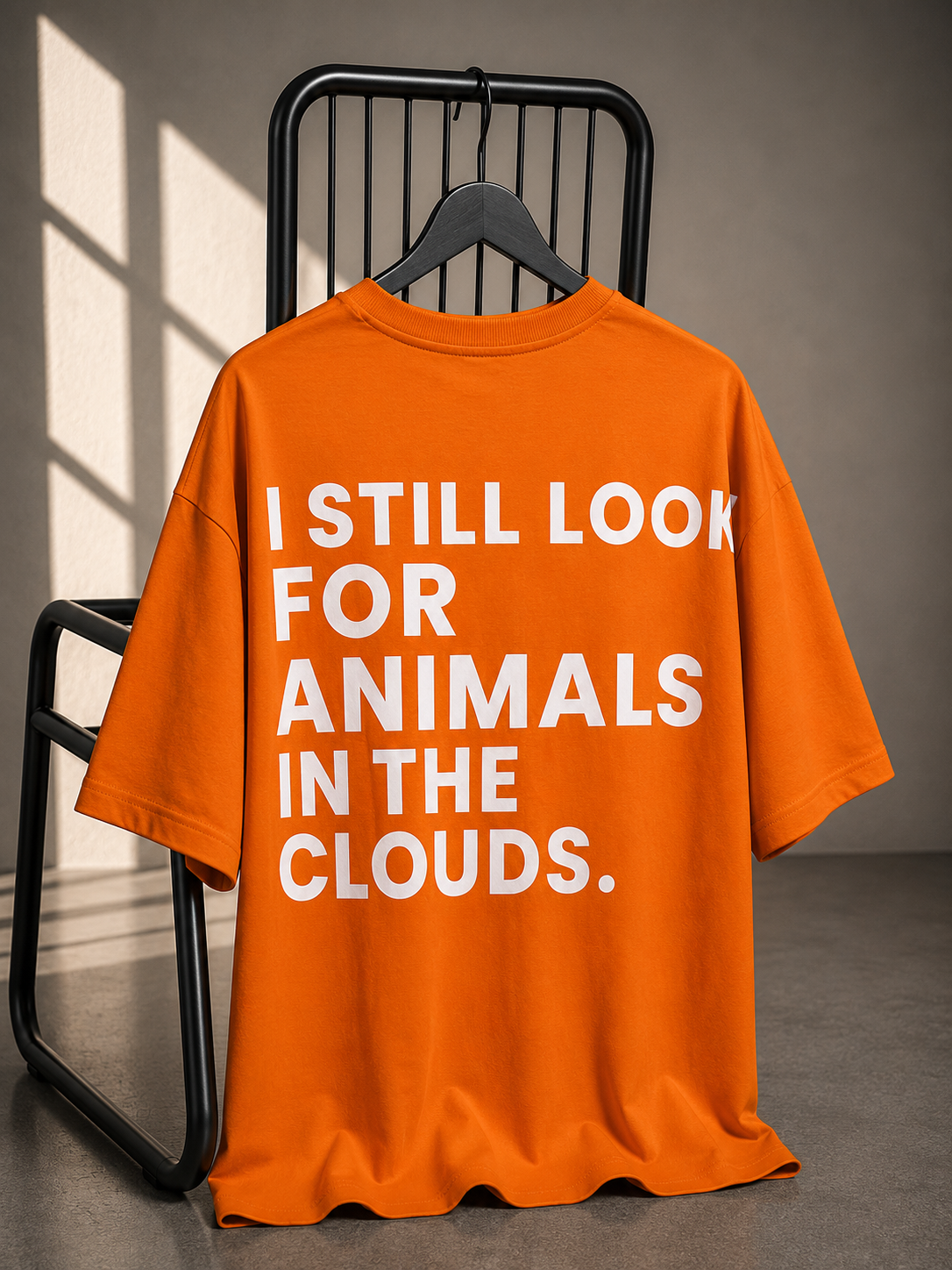 Orange oversized unisex T-shirt featuring bold "I Still Look for Animals in the Clouds" typography back print on heavyweight French Terry cotton.