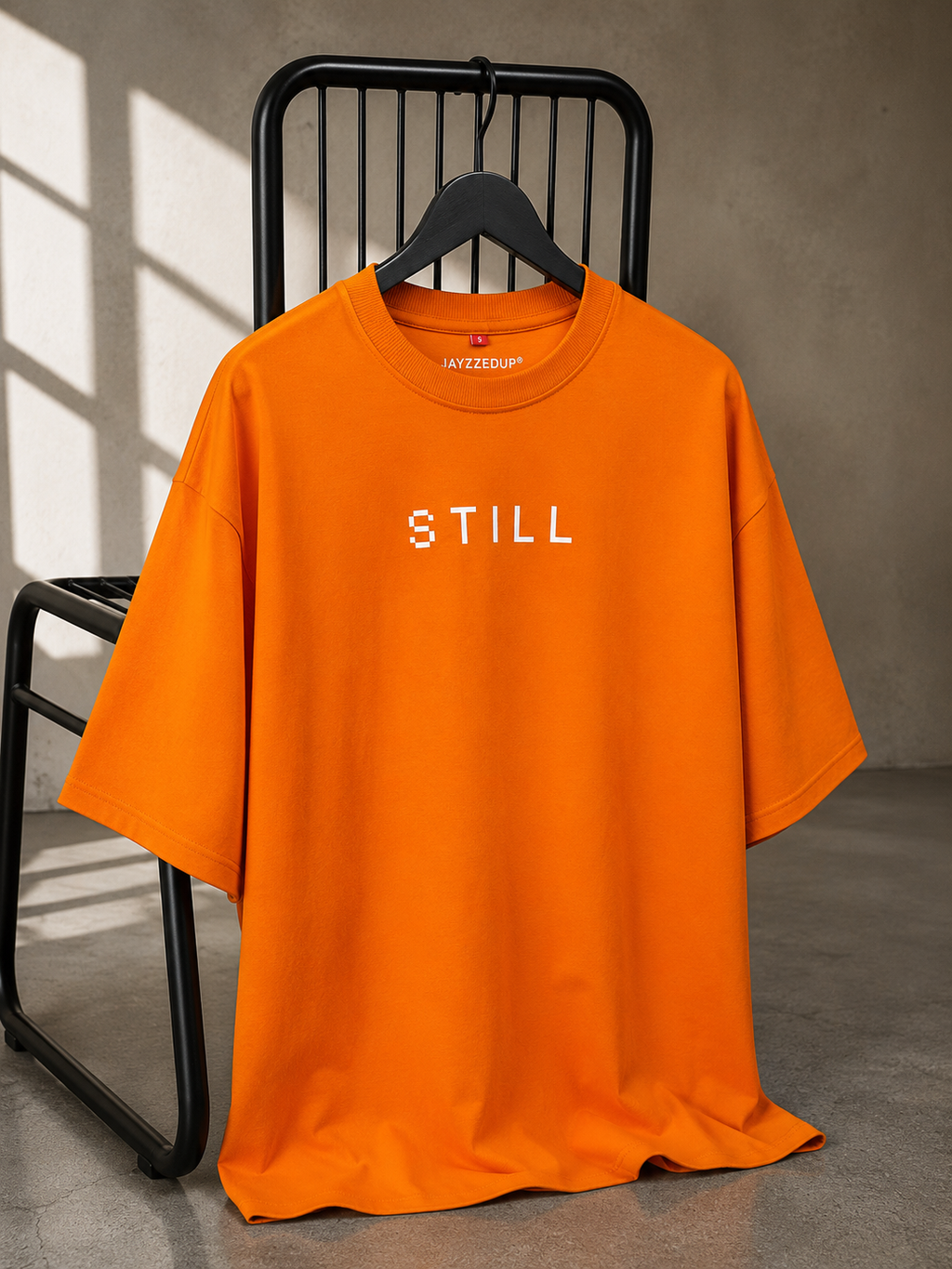 Orange oversized unisex typography T-shirt with minimal "Still" front print, made from 220–240 GSM bio-washed French Terry cotton.
