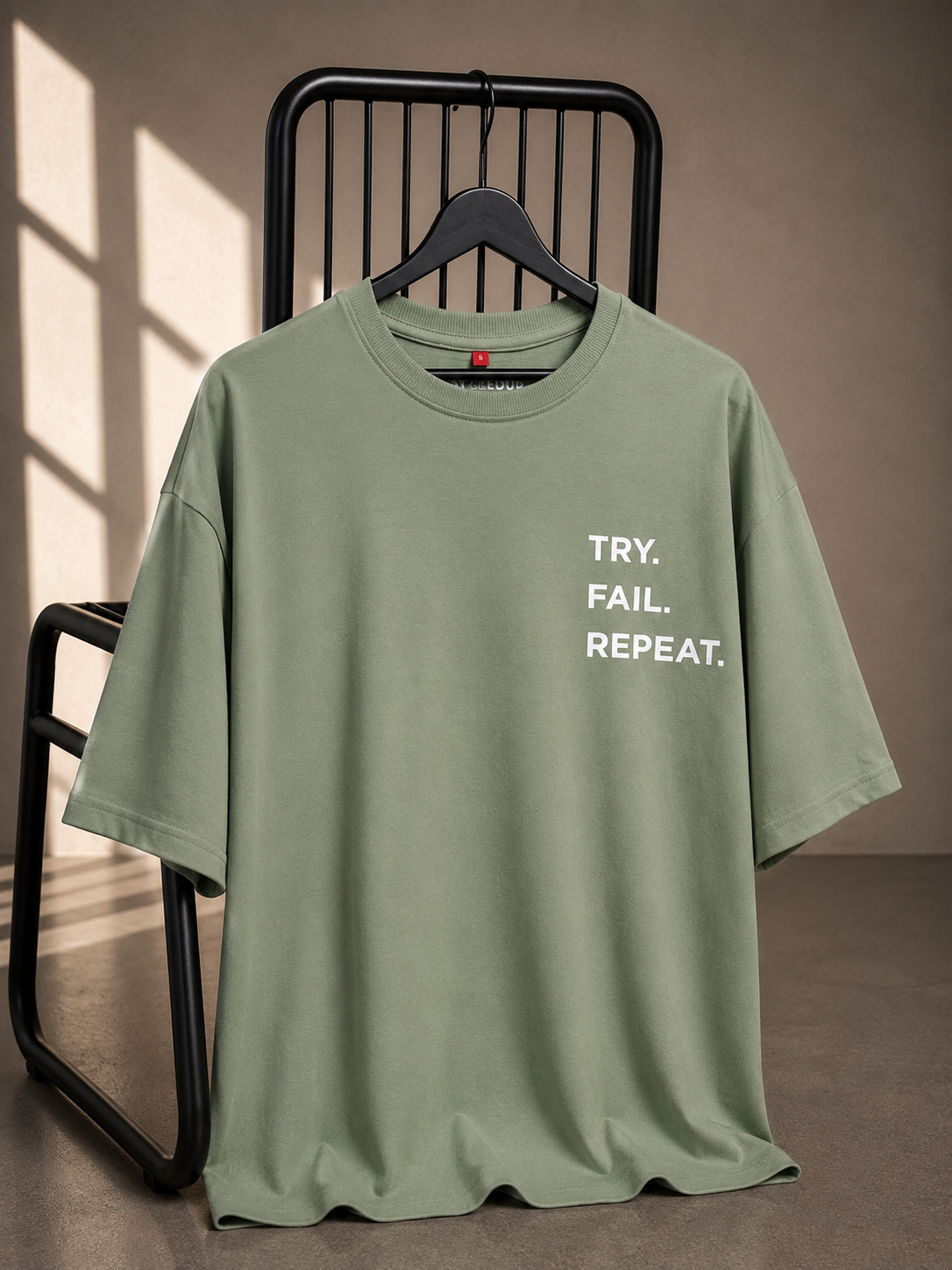 Sage green oversized unisex T-shirt featuring the "Try. Fail. Repeat." motivational typography on the chest, made from 220–240 GSM bio-washed French Terry cotton.
