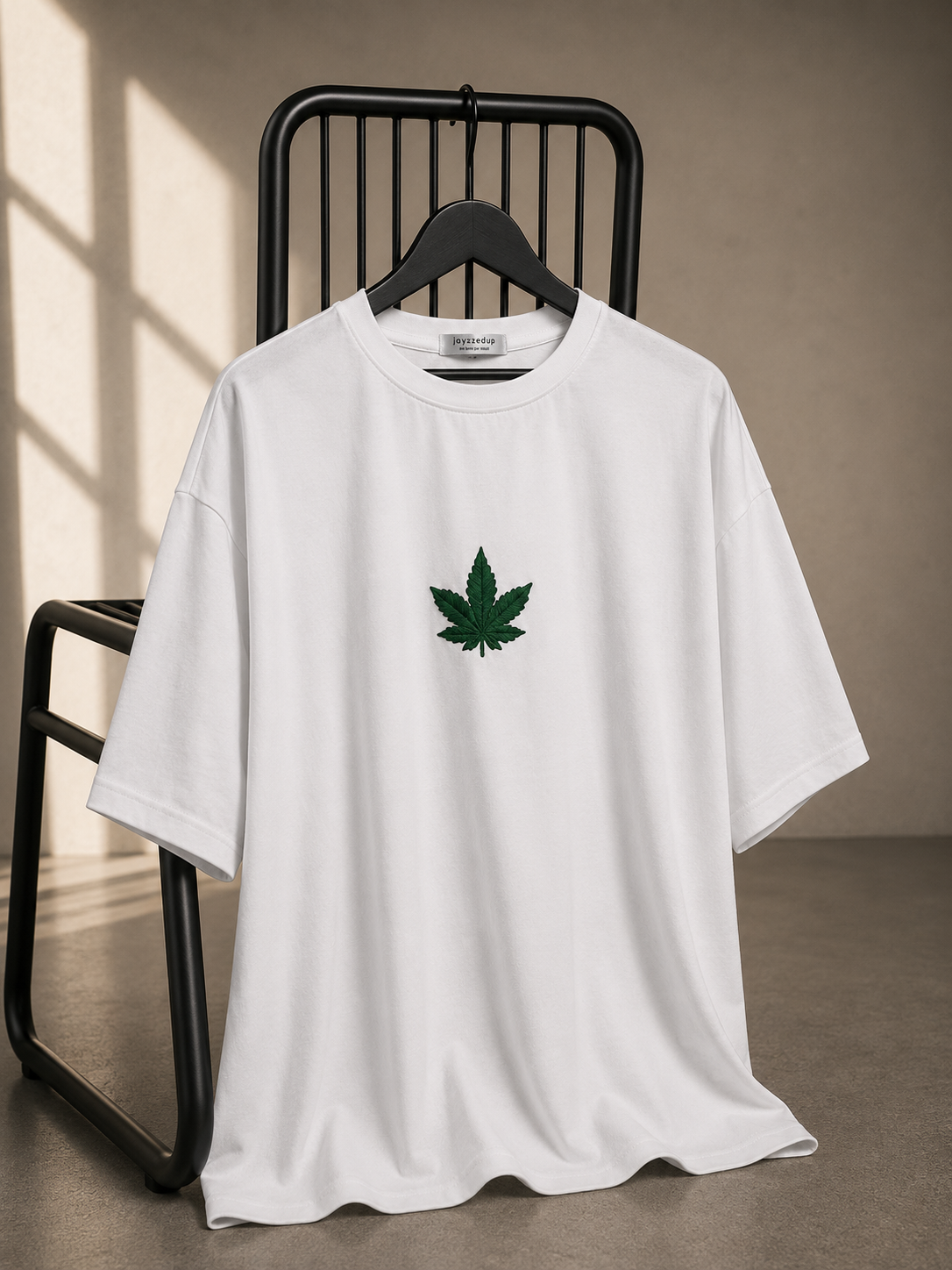 White oversized unisex T-shirt featuring a minimal embroidered leaf graphic on the chest, crafted from 220–240 GSM bio-washed French Terry cotton.